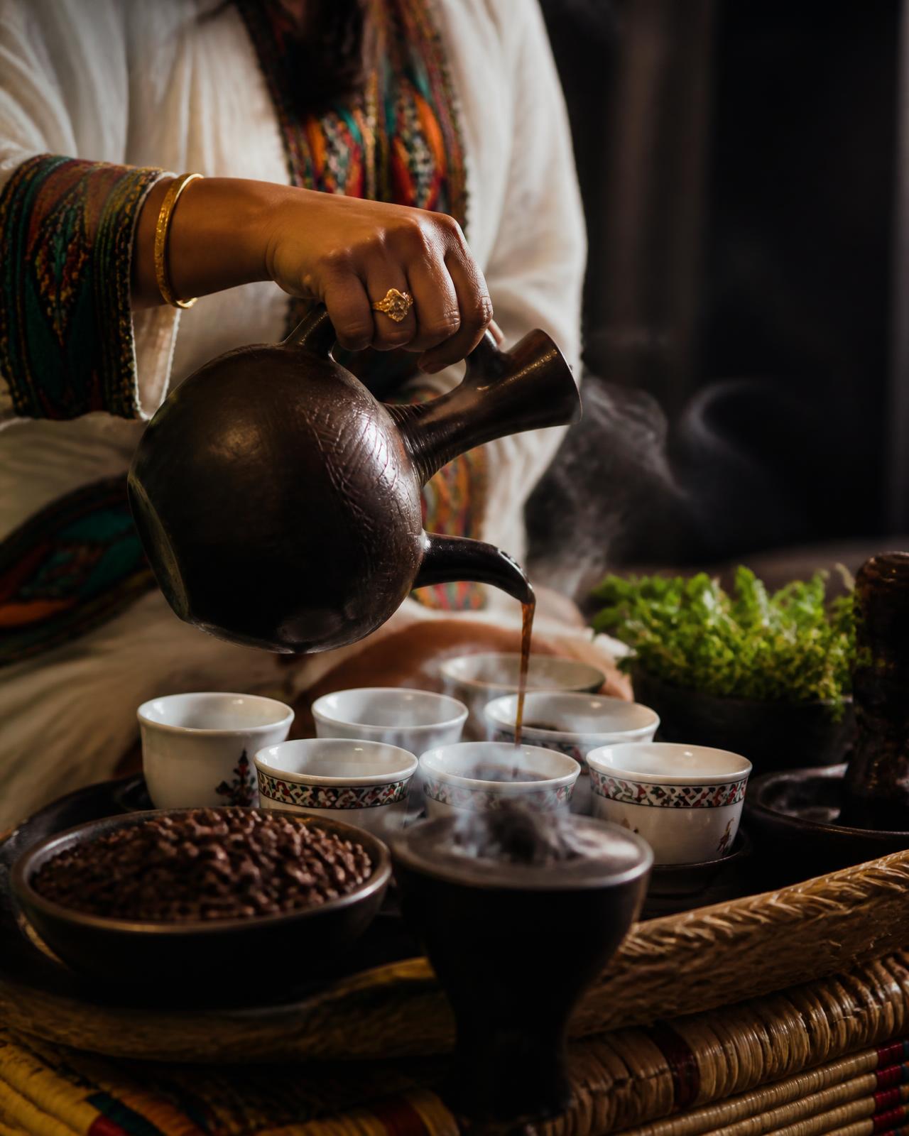 Hands pouring Ethiopian coffee from a clay jebena during a traditional coffee ceremony