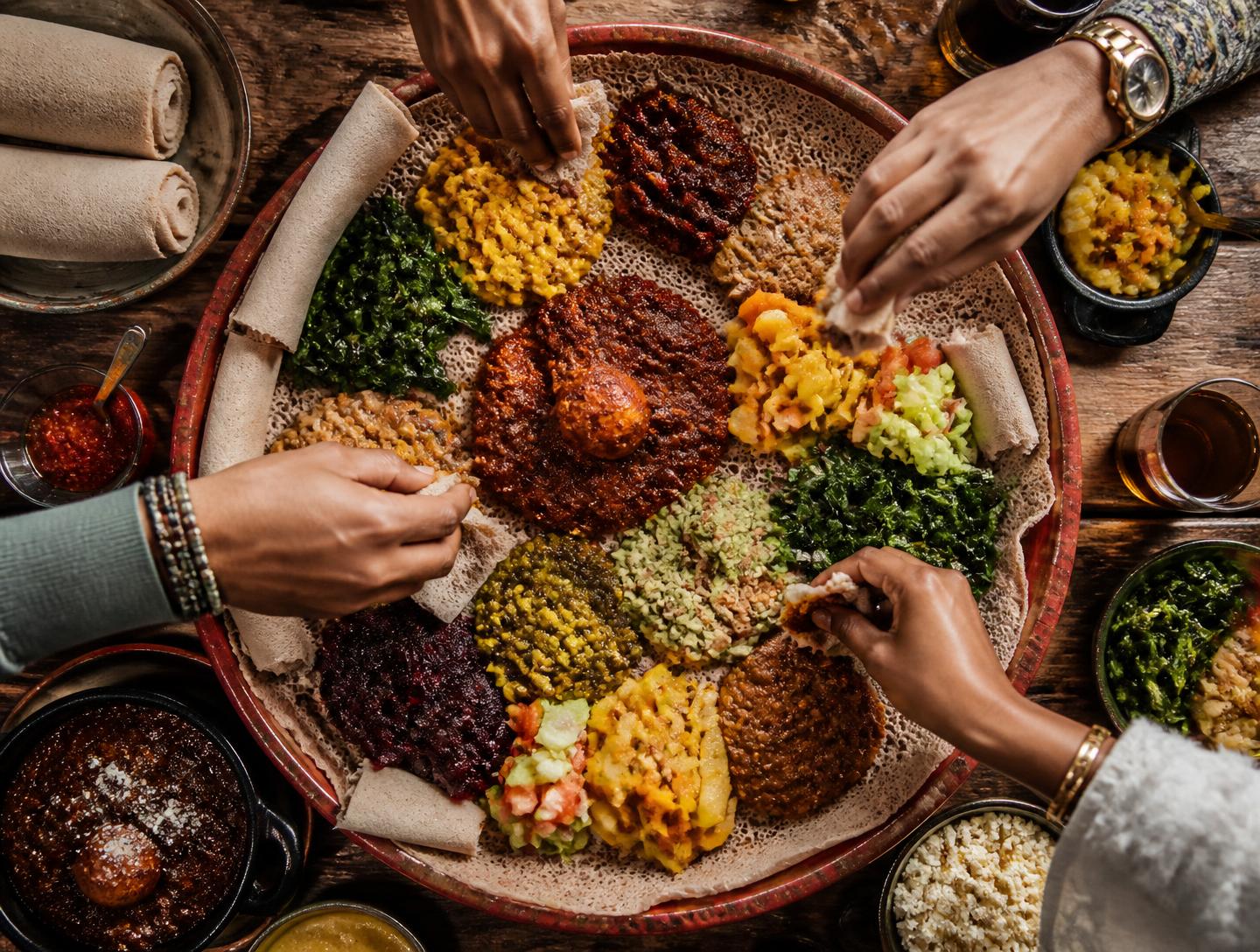 Overhead view of a shared Ethiopian injera platter with colourful stews